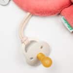 imagen de un chupete enganchado al Sujeta chupetes Jeanne Mini peluche que brilla en la oscuridad