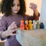 imagen de una niña y las figuras Grapat animales de madera