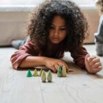 imagen de una niña jugando con el set Grapat 18 árboles de madera para juego simbólico
