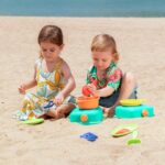imagen de una niña y un niño jugando en la playa con la Cocina de playa portátil de Hape con accesorios