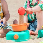 imagen de una niña y un niño en la playa jugando con la Cocina de playa portátil de Hape con accesorios