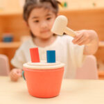 imagen de una niña con el Cubo de golpeo con martillo de madera de Plantoys