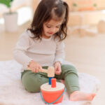 imagen de una niña jugando con el Cubo de golpeo con martillo de madera de Plantoys
