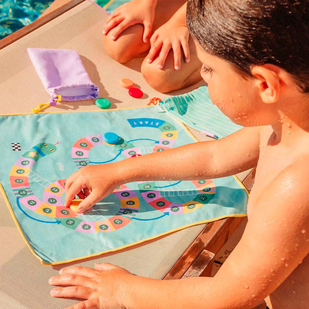 imagen de unos niños jugando con el Juego de playa 2 en 1 oca y serpientes y escaleras de Quut