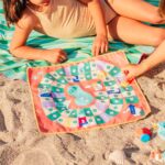 imagen de un grupo de niños jugando con el Juego de playa 2 en 1 oca y serpientes y escaleras de Quut