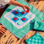 imagen de unos niños jugando con el Juego de playa 2 en 1 Parchís y Tres en Raya de Quut