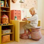 imagen de una niña usando el Stapelstein Set completo de asiento y equilibrio como asiento de estudio